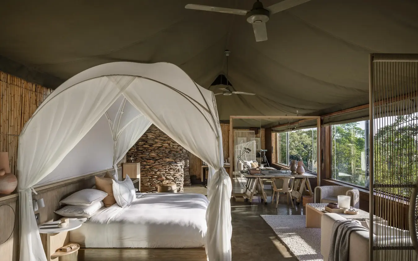 Luxury bedroom with white canopy bed and stone fireplace, Singita Faru Faru Lodge, Serengeti National Park, Tanzania