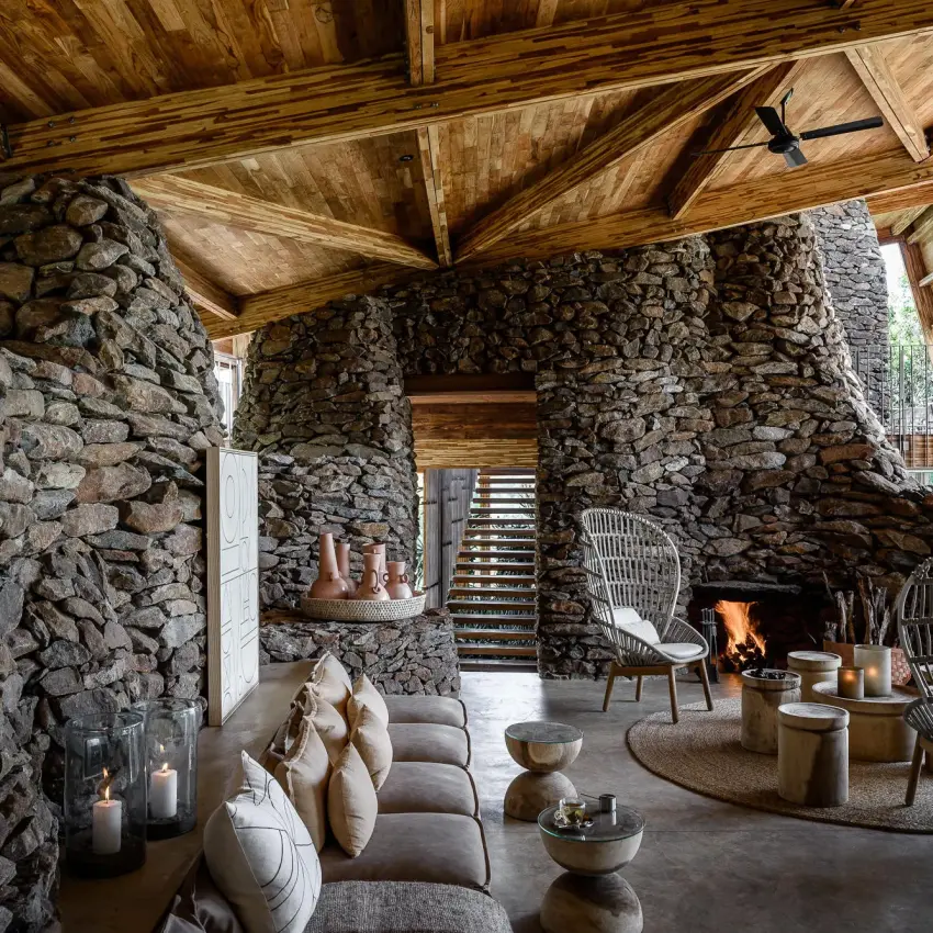 Stone fireplace lounge with wooden ceiling and seating, Singita Faru Faru Lodge, Serengeti National Park, Tanzania