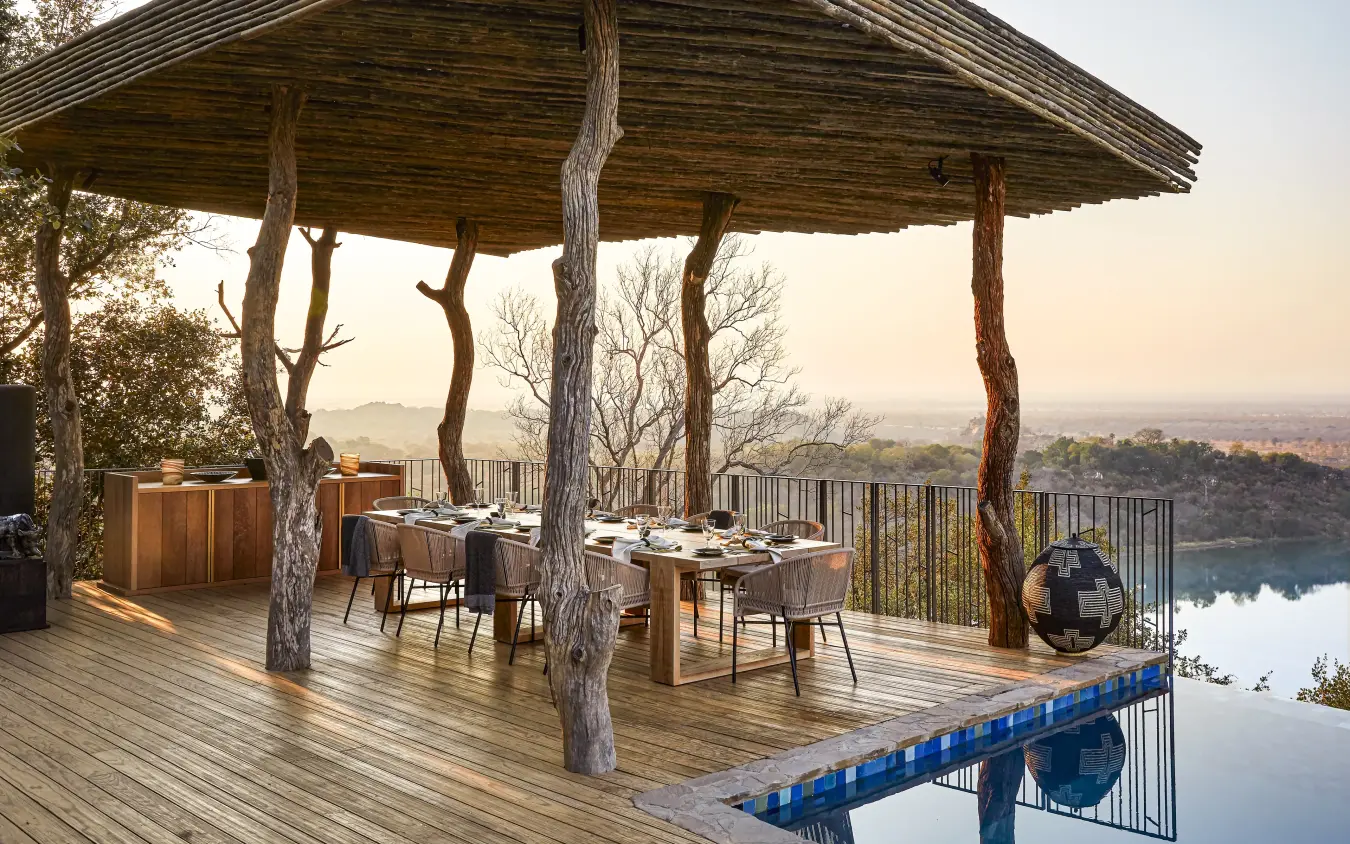Elevated dining deck with thatched roof overlooking river valley at sunset, Singita Malilangwe House, Gonarezhou & Malilangwe, Zimbabwe