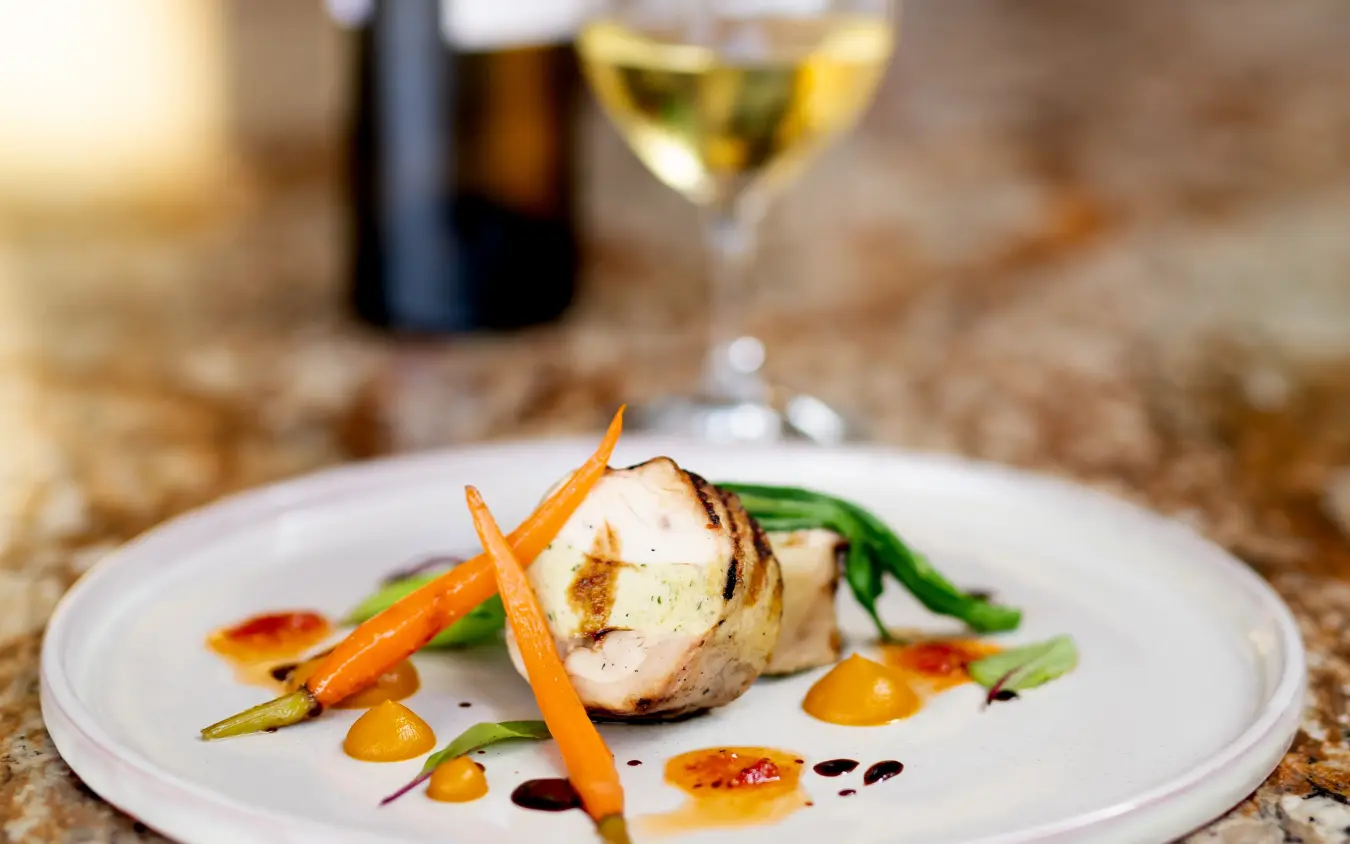 Fine dining plated dish with seafood and vegetables alongside wine service, Singita Malilangwe House, Gonarezhou & Malilangwe, Zimbabwe