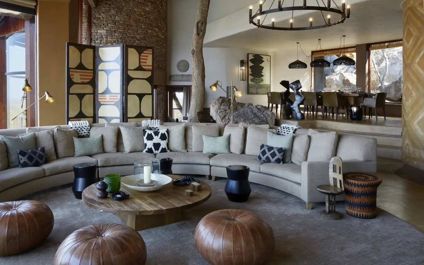 Curved sectional sofa with leather poufs in modern lodge interior, Singita Malilangwe House, Gonarezhou & Malilangwe, Zimbabwe