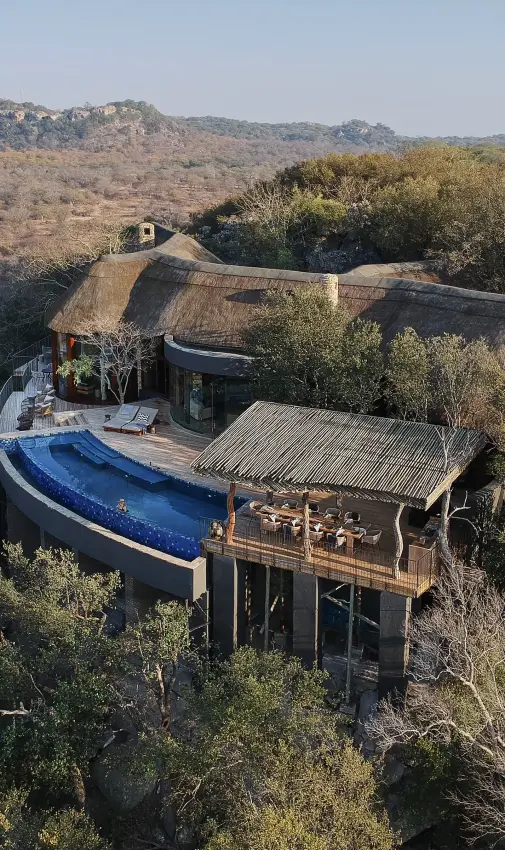 Luxury lodge with infinity pool overlooking savanna landscape and rocky hills, Singita Malilangwe House, Gonarezhou & Malilangwe, Zimbabwe