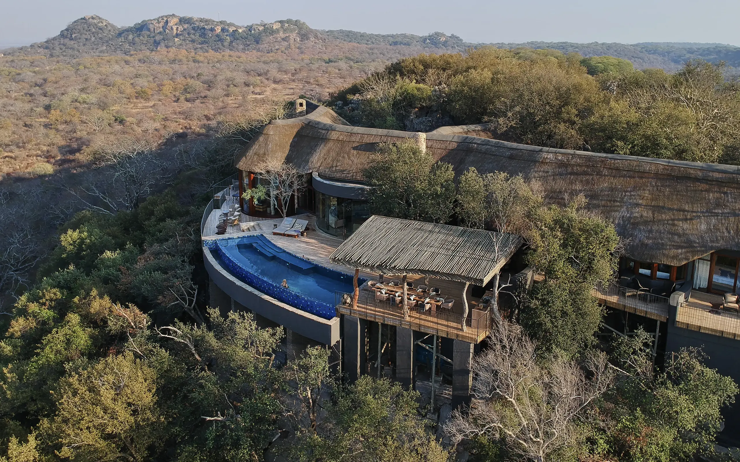 Luxury lodge with infinity pool overlooking savanna landscape and rocky hills, Singita Malilangwe House, Gonarezhou & Malilangwe, Zimbabwe