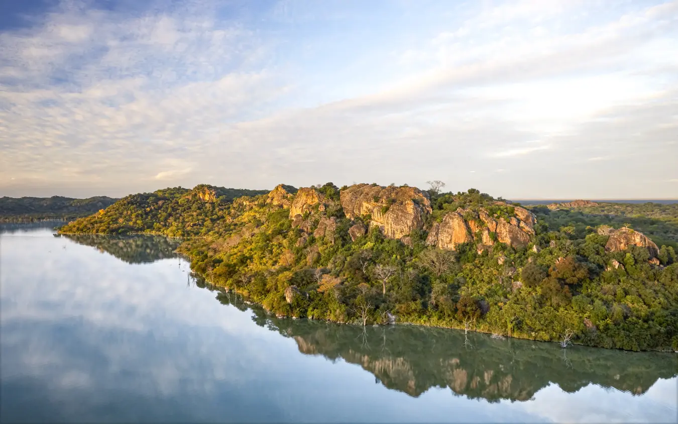 Scenic river landscape with forested cliffs reflecting in calm water, Singita Malilangwe House, Gonarezhou & Malilangwe, Zimbabwe