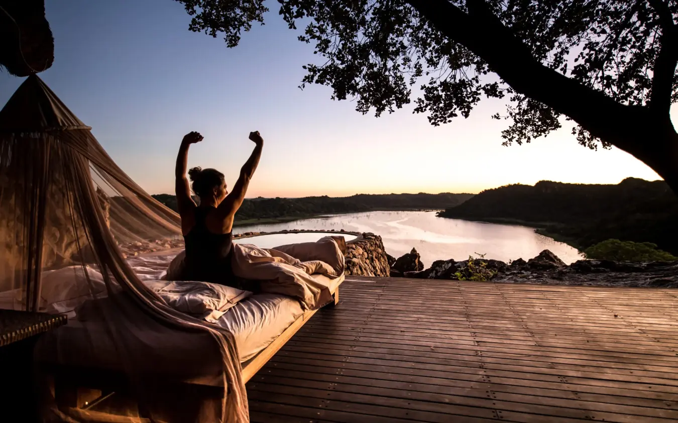 Woman stretching in hammock overlooking river at sunset, Singita Pamushana, Gonarezhou & Malilangwe, Zimbabwe