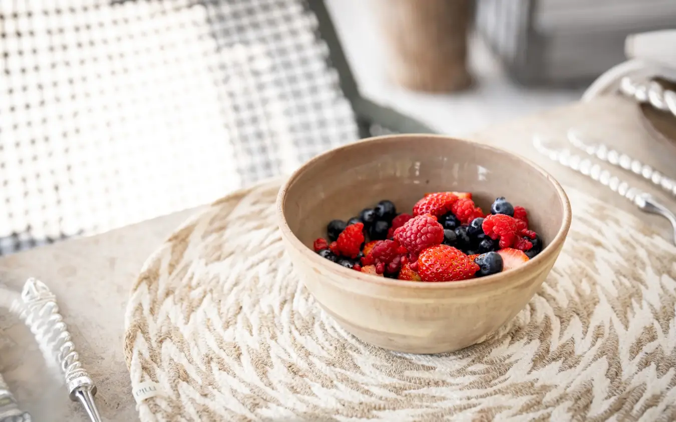 Bowl of fresh berries on woven placemat at table, Singita Pamushana, Gonarezhou & Malilangwe, Zimbabwe