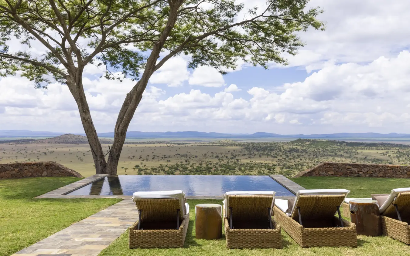 Infinity pool and lounge chairs overlooking African savanna landscape, Singita Sasakwa Lodge, Serengeti National Park, Tanzania