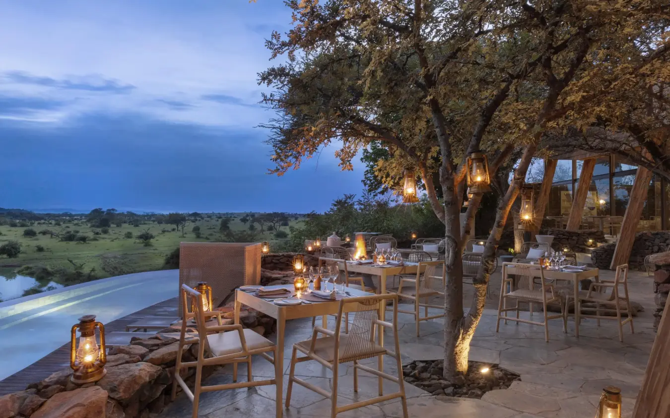 Outdoor dining deck overlooking savanna at dusk, Singita Sasakwa Lodge, Serengeti National Park, Tanzania