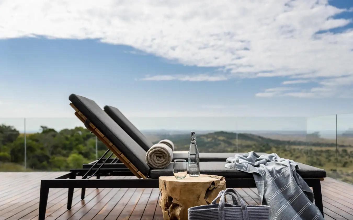 Lounge chairs with refreshments overlooking savanna landscape, Singita Sasakwa Lodge, Serengeti National Park, Tanzania
