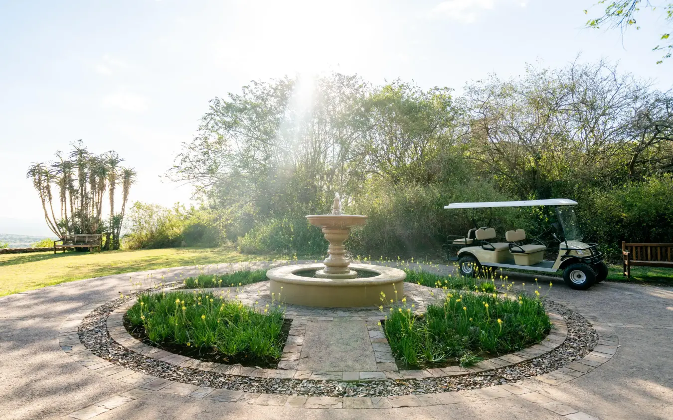 Central fountain courtyard with manicured gardens and golf cart, Singita Sasakwa Lodge, Serengeti National Park, Tanzania