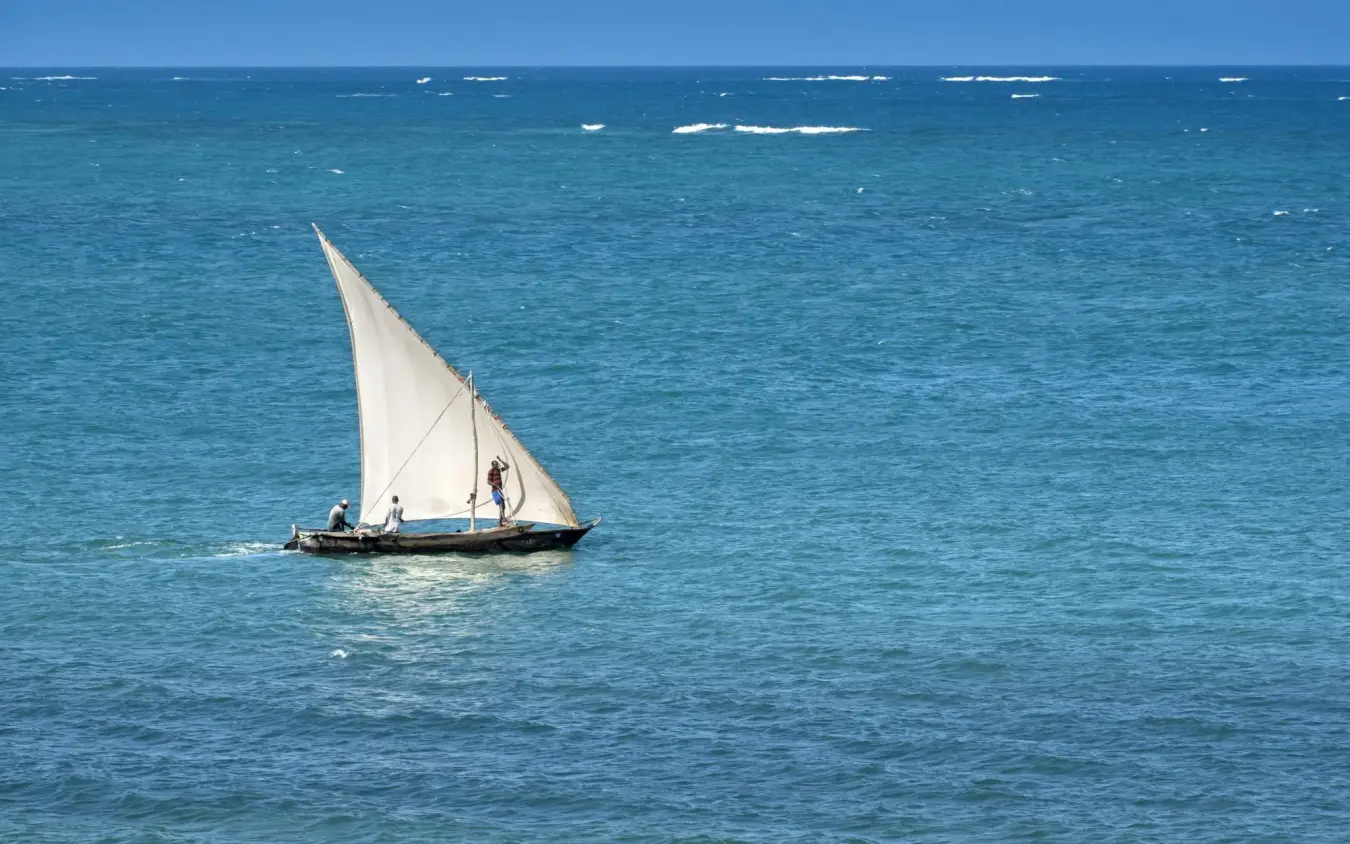 Traditional sailing dhow with white sail on turquoise ocean, Sirai Beach, Kilifi, Kenya