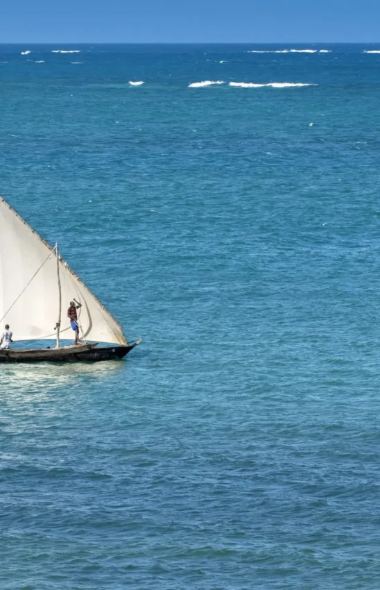 Traditional sailing dhow with white sail on turquoise ocean, Sirai Beach, Kilifi, Kenya