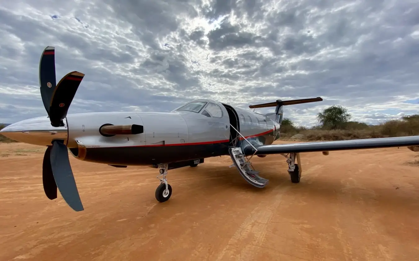 Private aircraft parked on red earth airstrip under cloudy sky, Sirai Beach, Kilifi, Kenya