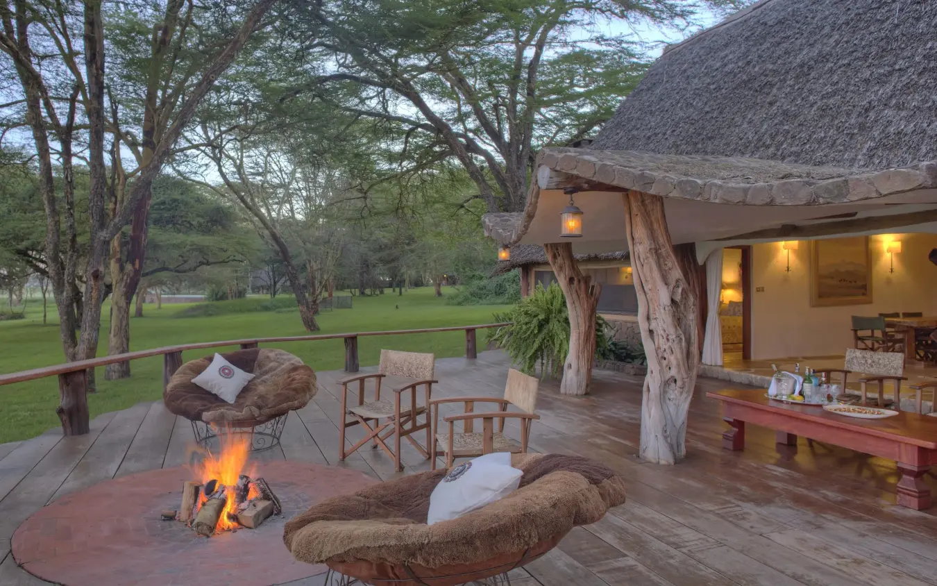 Safari lodge deck with fire pit overlooking grassland at dusk, Sirikoi, Laikipia Highlands, Kenya