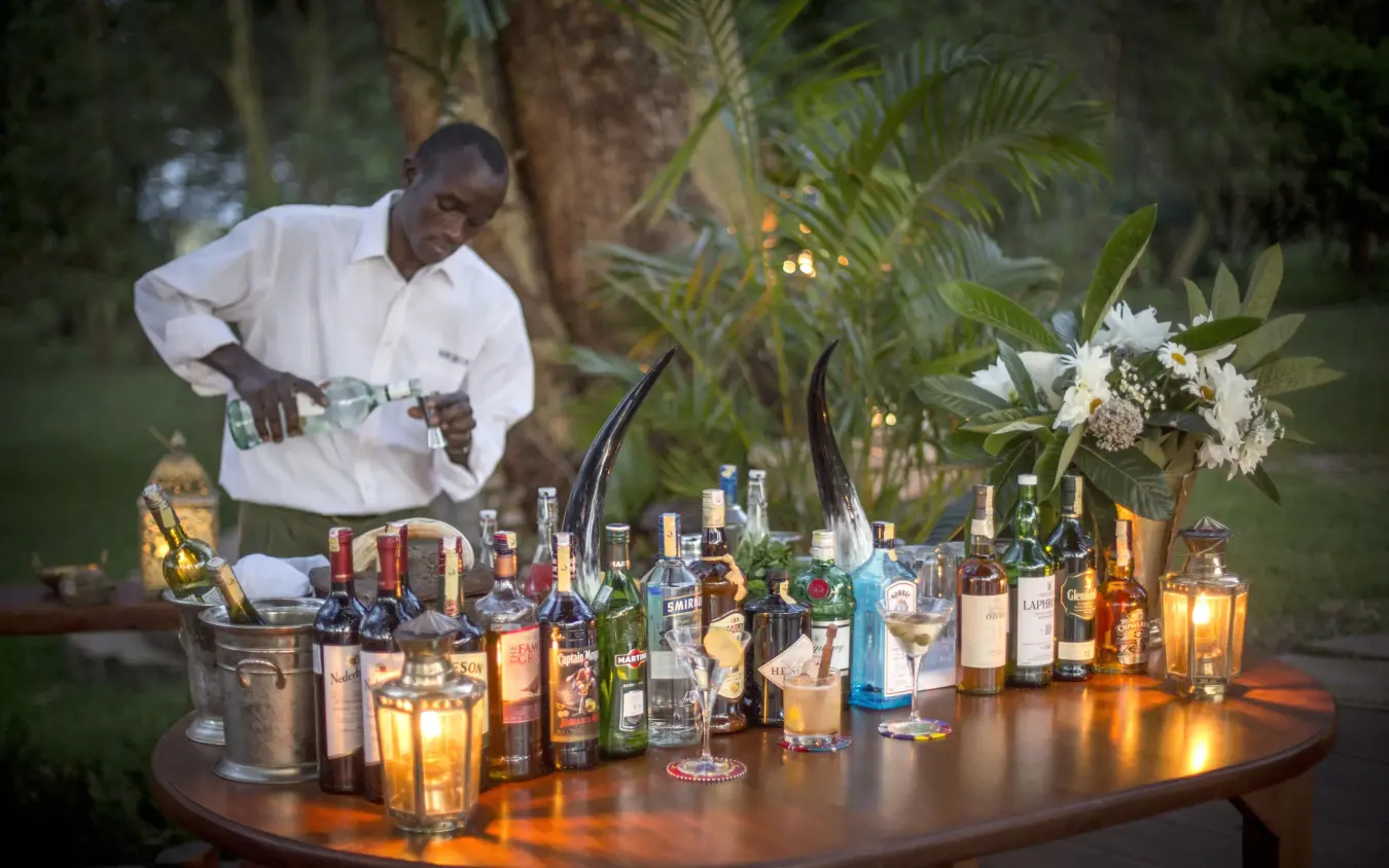 Bartender preparing drinks at outdoor evening service table, Sirikoi, Laikipia Highlands, Kenya