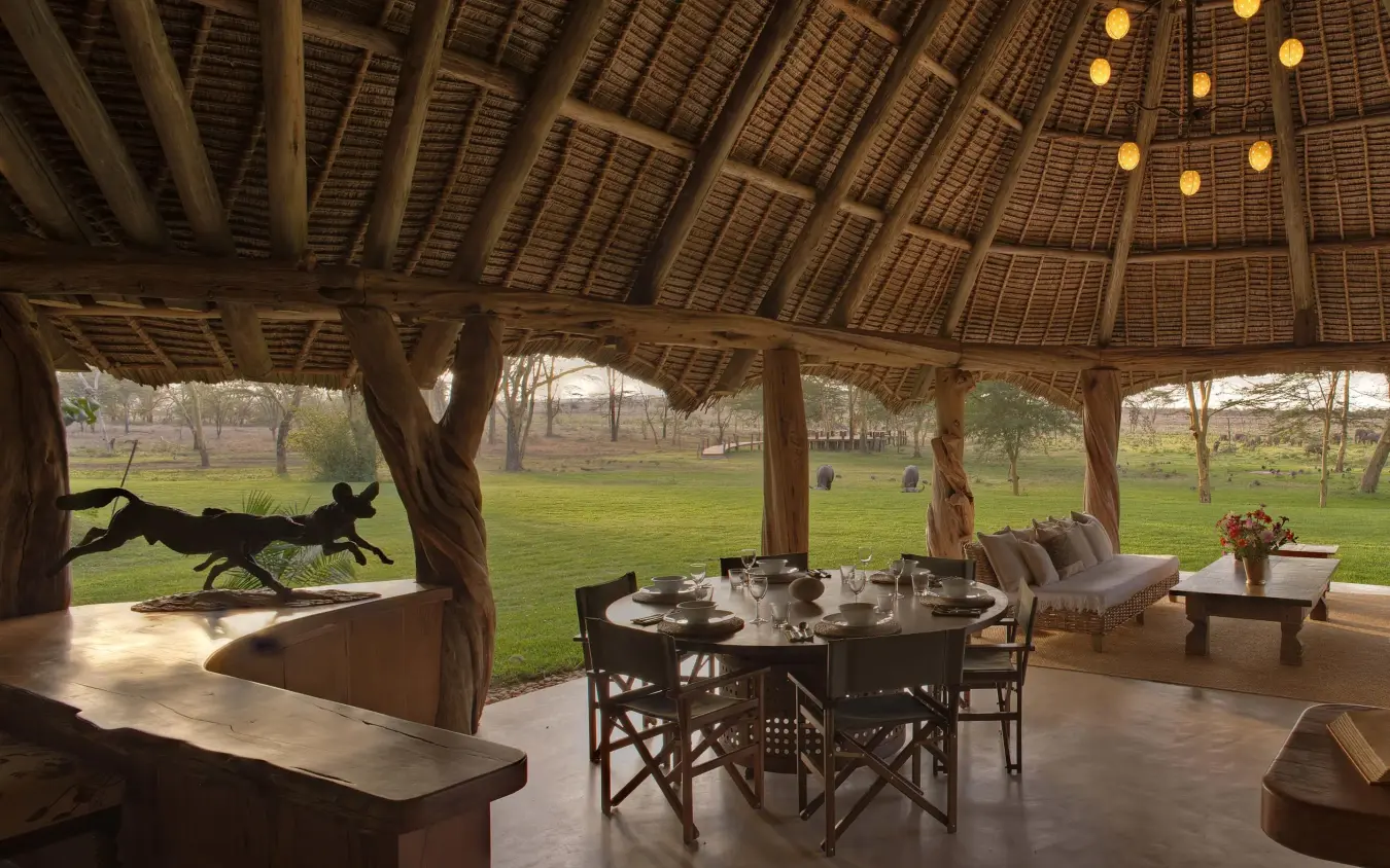 Open-sided thatched pavilion with dining and lounge seating overlooking grassland, Sirikoi, Laikipia Highlands, Kenya