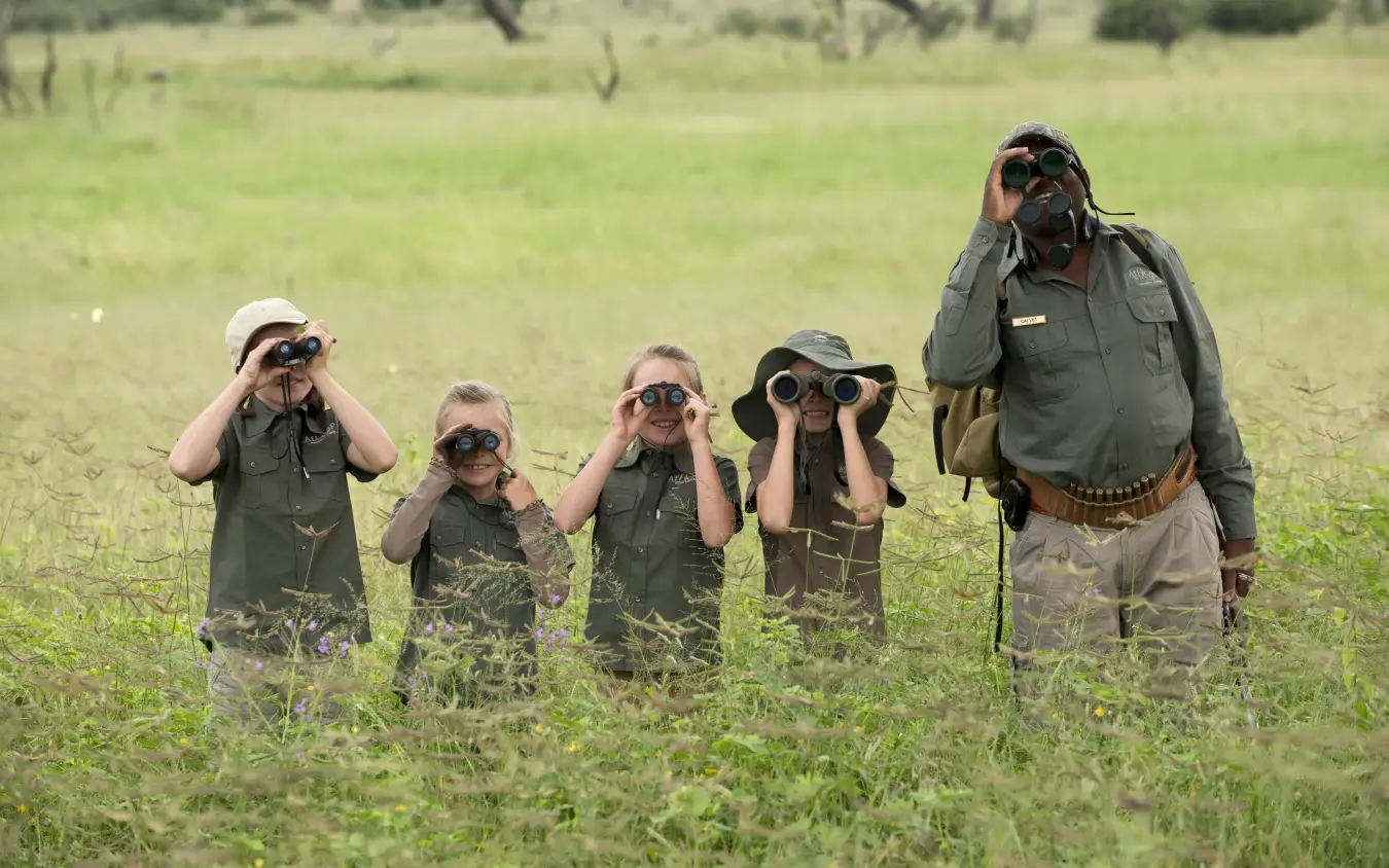 Family group observing wildlife through binoculars in savanna, Somalisa Acacia, Hwange National Park, Zimbabwe