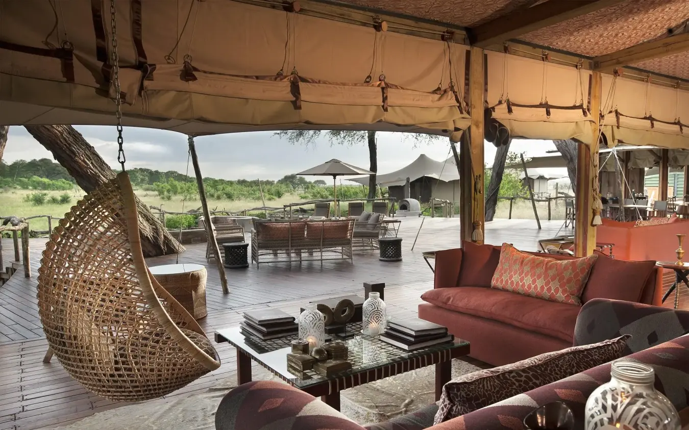 Covered lounge area with hanging chair overlooking savanna landscape, Somalisa Acacia, Hwange National Park, Zimbabwe