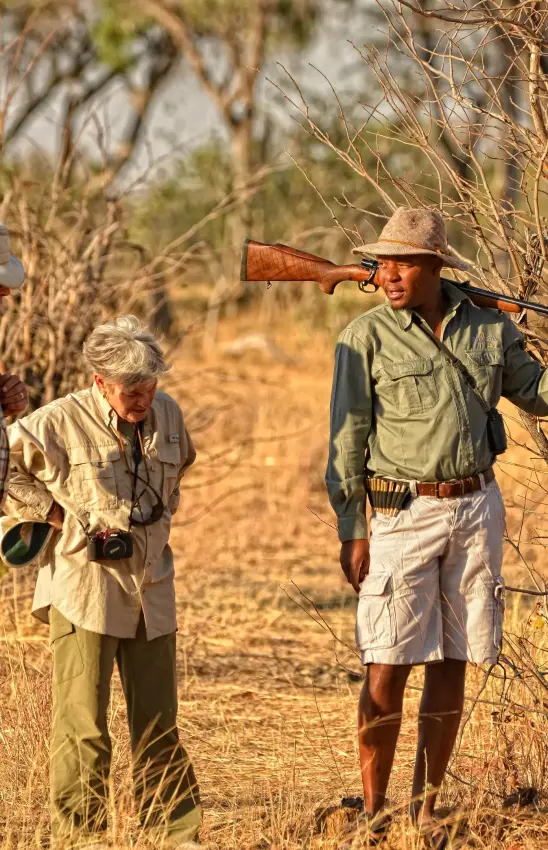 Guides demonstrating hunting rifle technique in bush setting, Somalisa Acacia, Hwange National Park, Zimbabwe