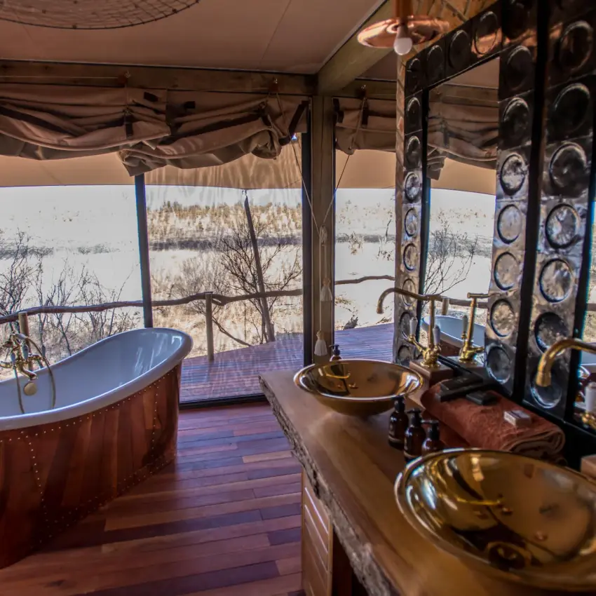 Luxury bathroom with copper soaking tub overlooking waterhole, Somalisa Camp, Hwange National Park, Zimbabwe