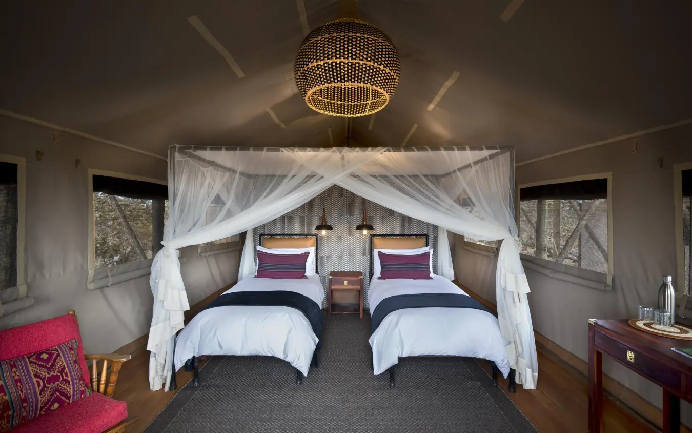 Luxury safari tent bedroom with twin canopy beds and draped curtains, Somalisa Expeditions, Hwange National Park, Zimbabwe