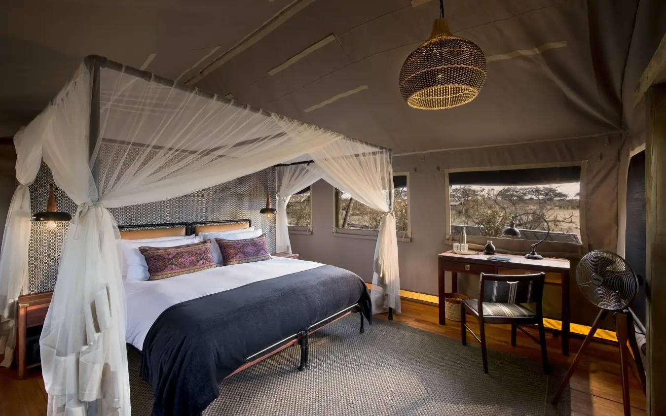 Bedroom with canopy bed and large windows overlooking savanna, Somalisa Expeditions, Hwange National Park, Zimbabwe