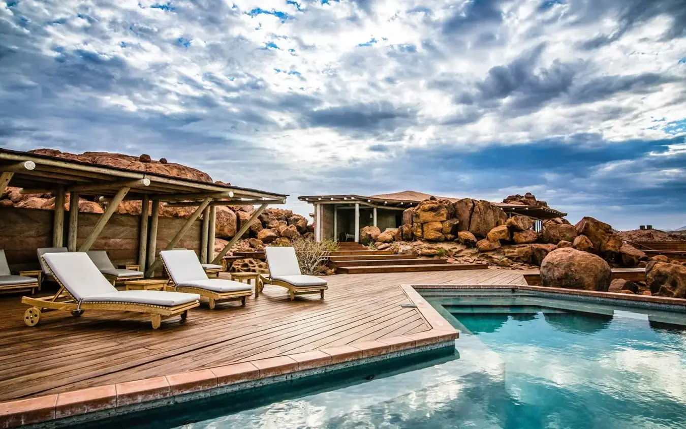 Swimming pool with loungers overlooking rocky desert landscape, Sorris Sorris, Damaraland, Namibia
