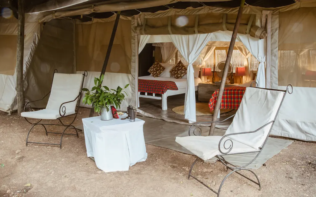 Safari camp tent with lounge chairs and bedroom visible, Speke’s Camp, Maasai Mara, Kenya