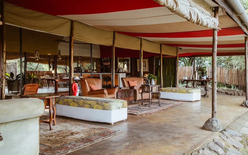 Open-air lounge with red canvas awning and leather seating, Speke’s Camp, Maasai Mara, Kenya