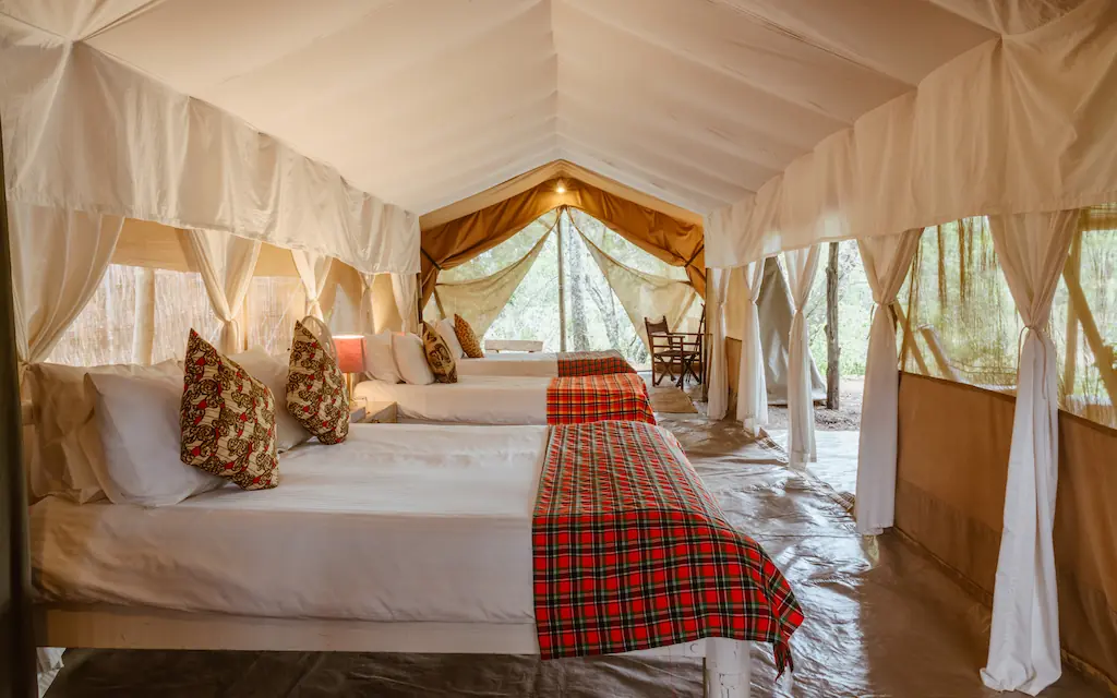 Luxury safari tent interior with draped canopy beds, Speke’s Camp, Maasai Mara, Kenya