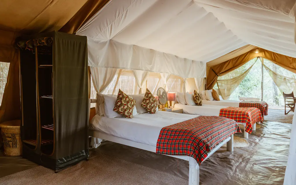 Canvas safari tent interior with multiple beds and furnishings, Speke’s Camp, Maasai Mara, Kenya