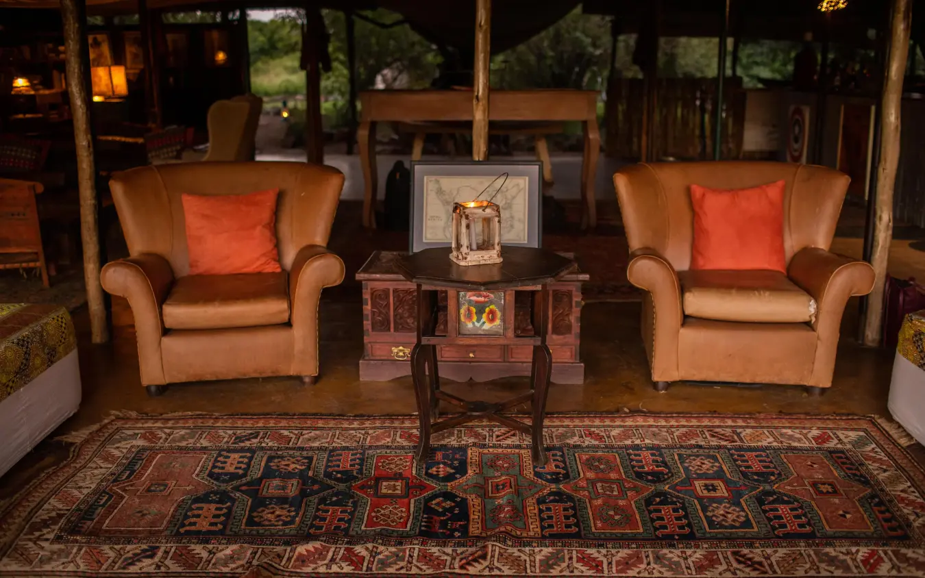 Elegant lounge with leather chairs and oriental rugs, Speke’s Camp, Maasai Mara, Kenya