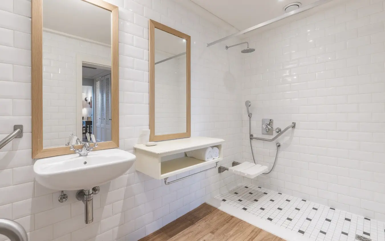 Modern bathroom with white subway tile, wooden-framed mirrors and rainfall showerhead, Strand Hotel Swakopmund, Swakopmund, Namibia