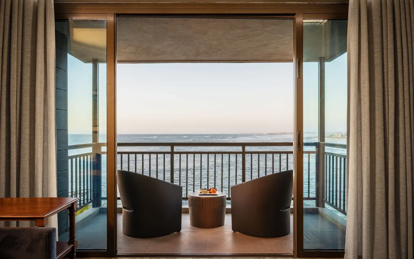 Beachfront balcony with lounge chairs overlooking calm ocean at dusk, Strand Hotel Swakopmund, Swakopmund, Namibia
