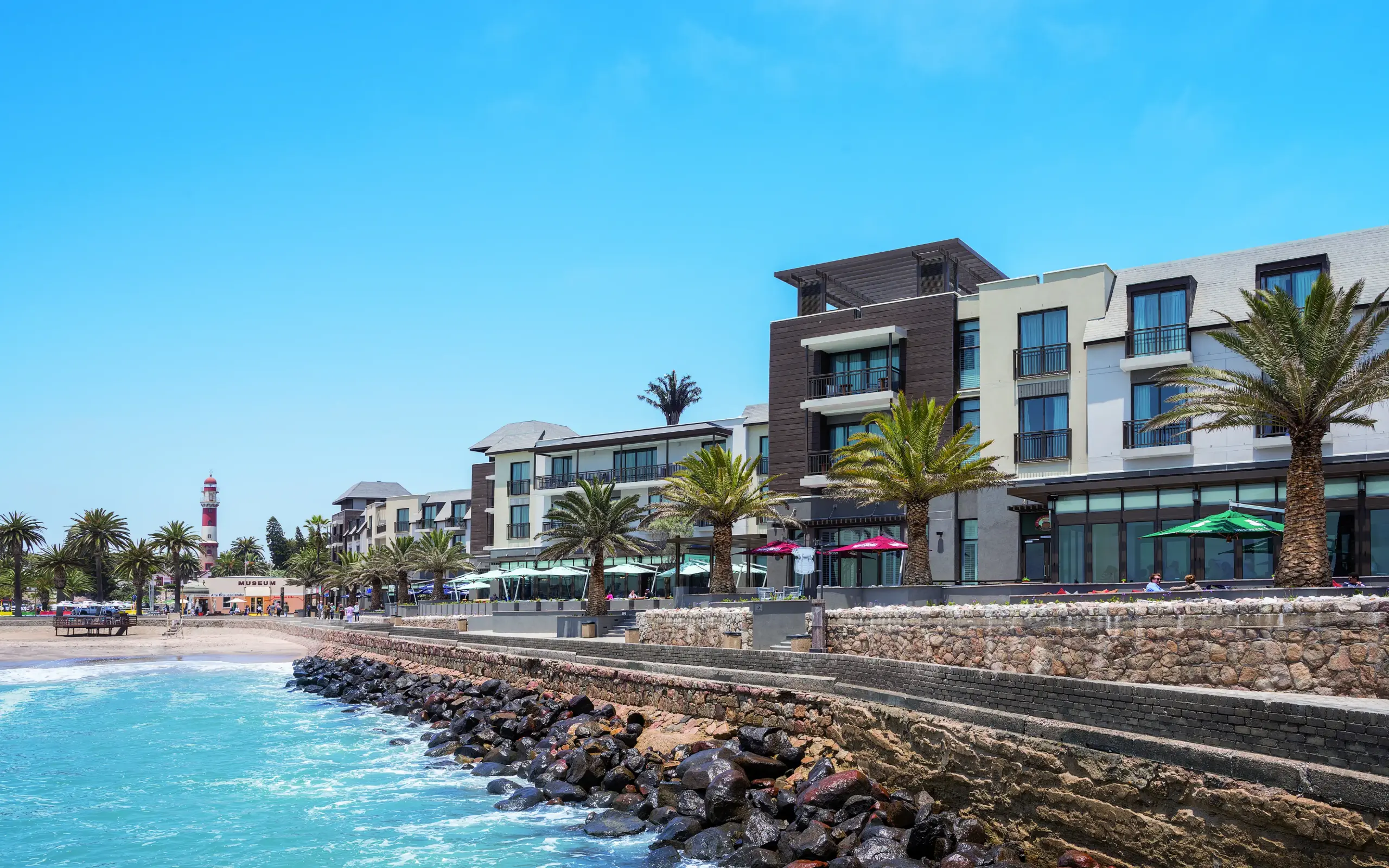 Beachfront resort buildings with rocky breakwater and turquoise water, Strand Hotel Swakopmund, Swakopmund, Namibia