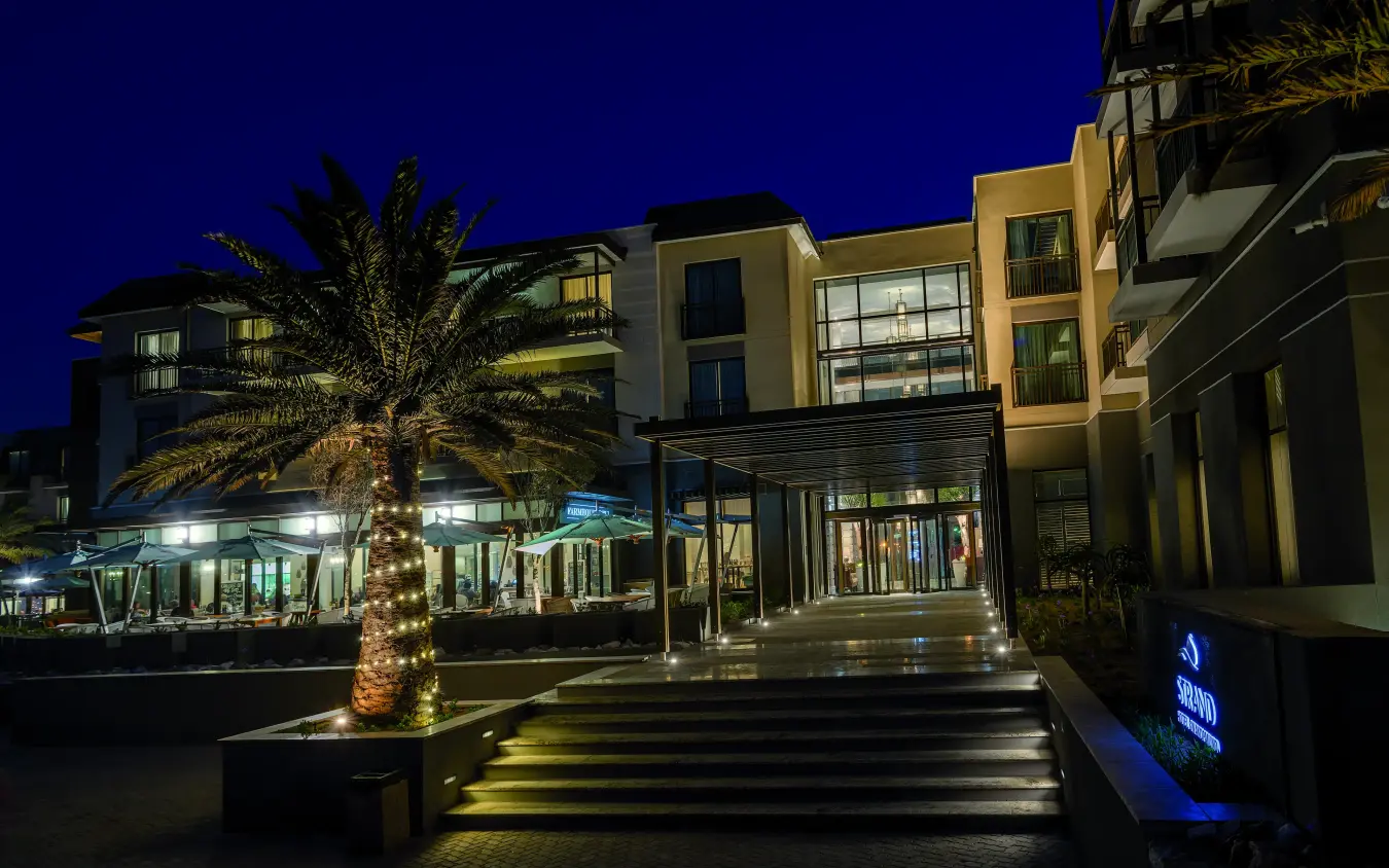 Illuminated modern resort courtyard with palm tree at dusk, Strand Hotel Swakopmund, Swakopmund, Namibia