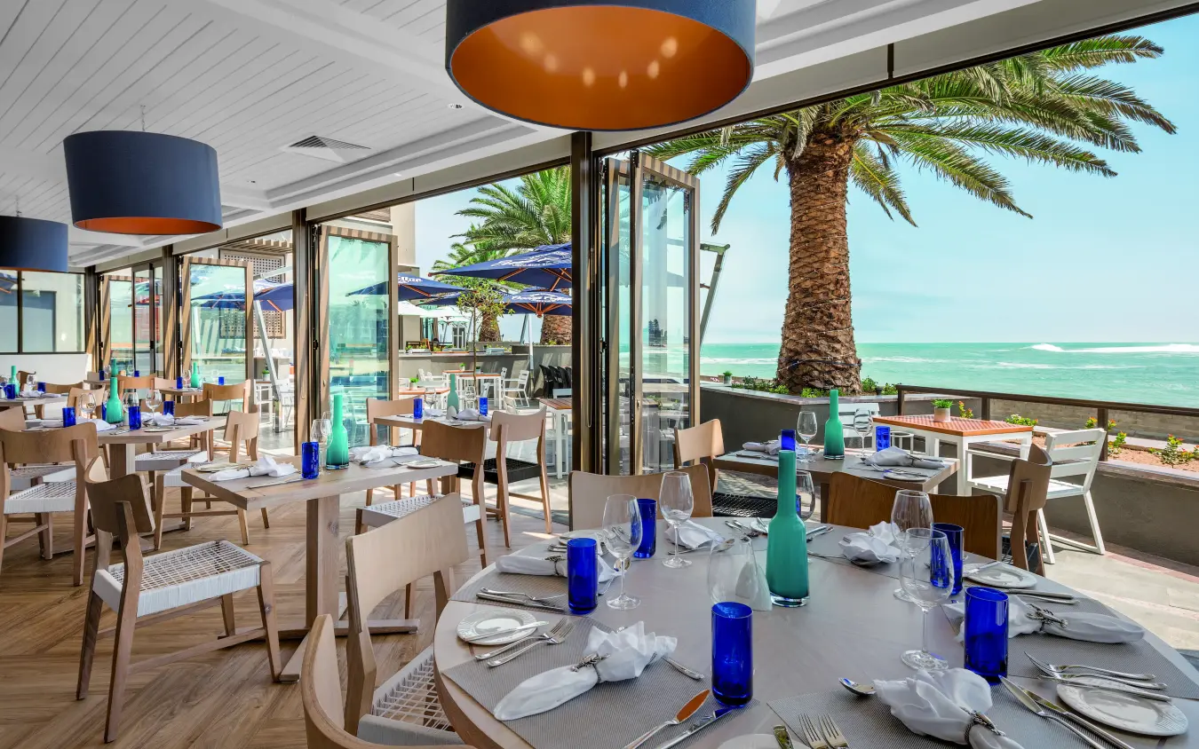 Beachfront restaurant with turquoise sea views and palm trees, Strand Hotel Swakopmund, Swakopmund, Namibia