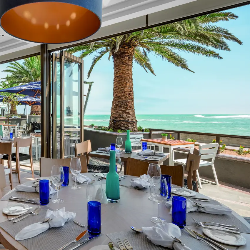 Beachfront restaurant with turquoise sea views and palm trees, Strand Hotel Swakopmund, Swakopmund, Namibia