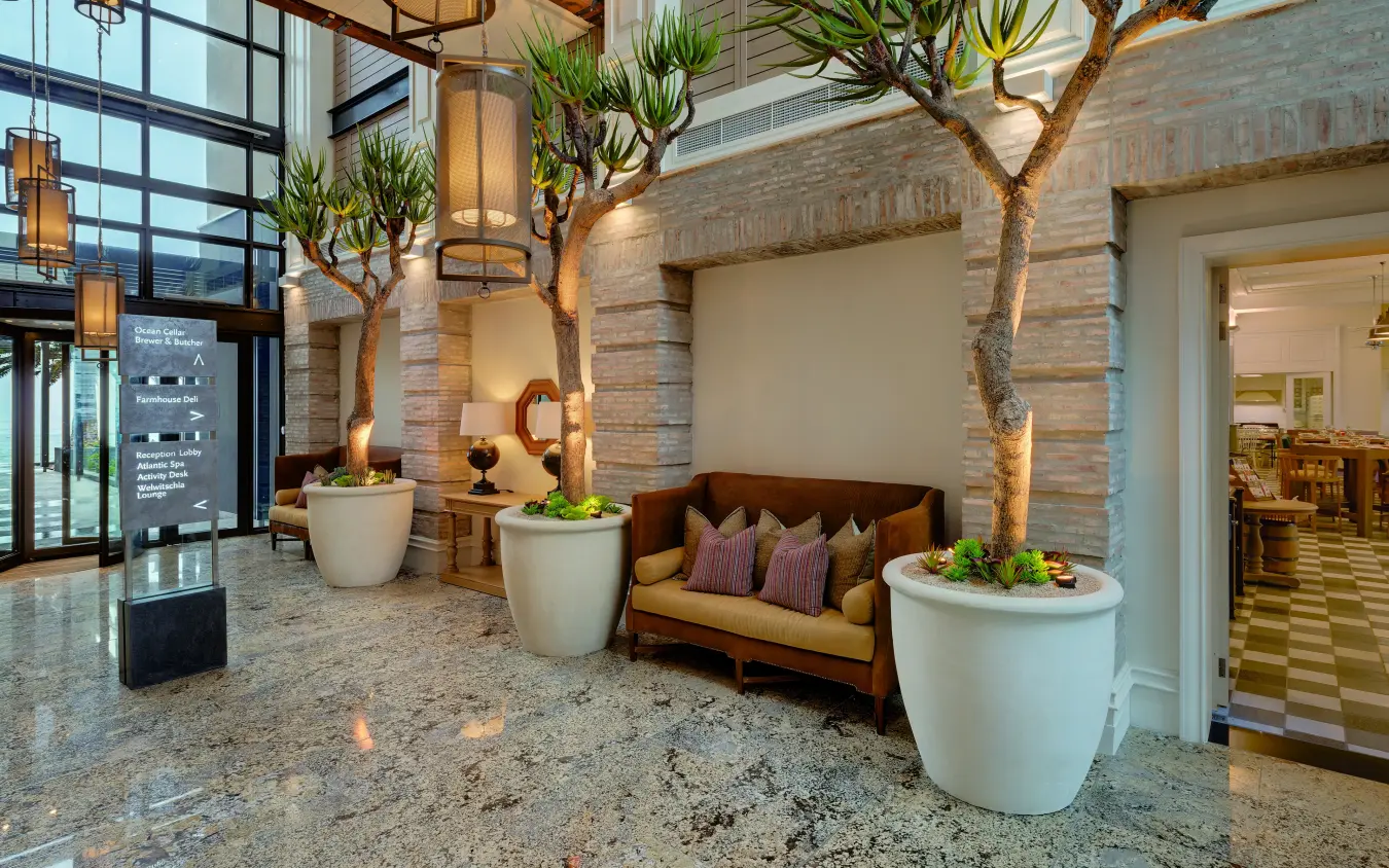 Modern lobby interior with potted trees and upholstered seating, Strand Hotel Swakopmund, Swakopmund, Namibia