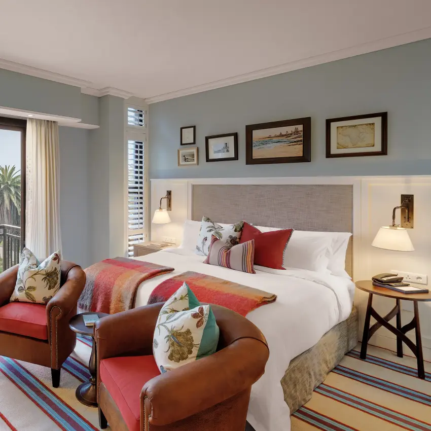 Luxury hotel bedroom with balcony overlooking palm trees and coastal gardens, Strand Hotel Swakopmund, Swakopmund, Namibia