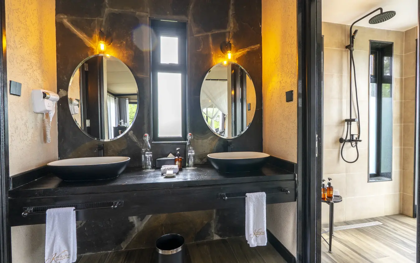 Double basin bathroom with black marble countertop and illuminated mirrors, Tarangire Elephant Springs, Tarangire National Park, Tanzania