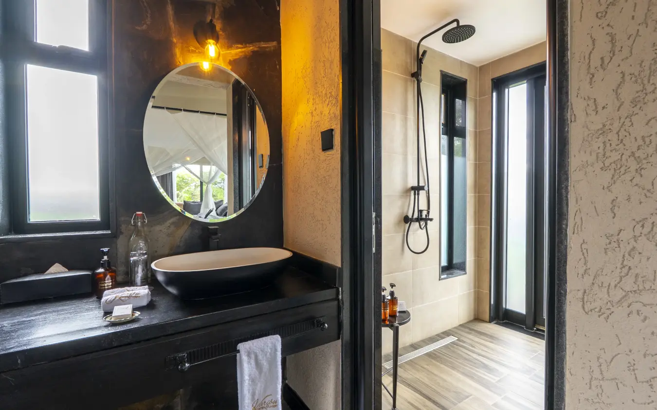 Modern bathroom with round mirror, black vanity and rainfall shower, Tarangire Elephant Springs, Tarangire National Park, Tanzania