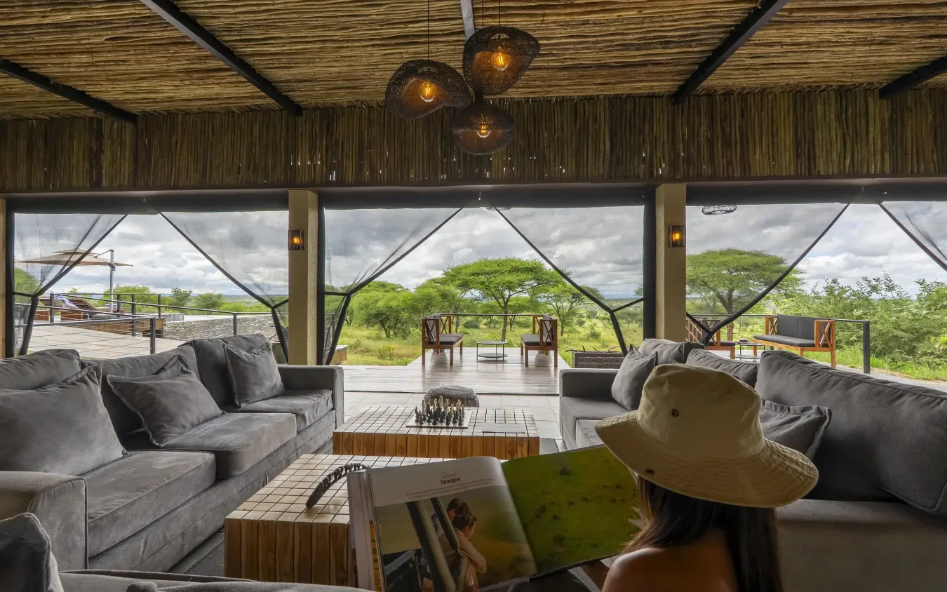Guest relaxing in safari lodge lounge overlooking acacia woodland savanna, Tarangire Elephant Springs, Tarangire National Park, Tanzania