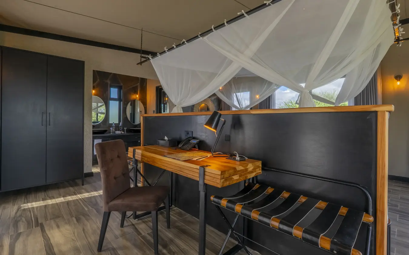 Luxury bedroom with canopy bed and work desk overlooking savanna landscape, Tarangire Elephant Springs, Tarangire National Park, Tanzania