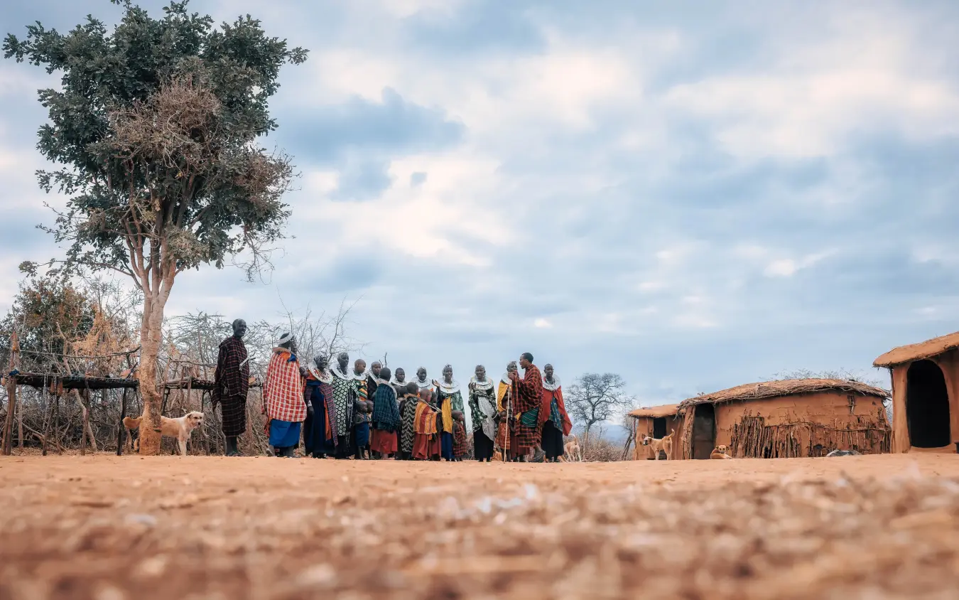 Group of villagers gathered in settlement with traditional mud huts, Tarangire Treetops, Tarangire National Park, Tanzania