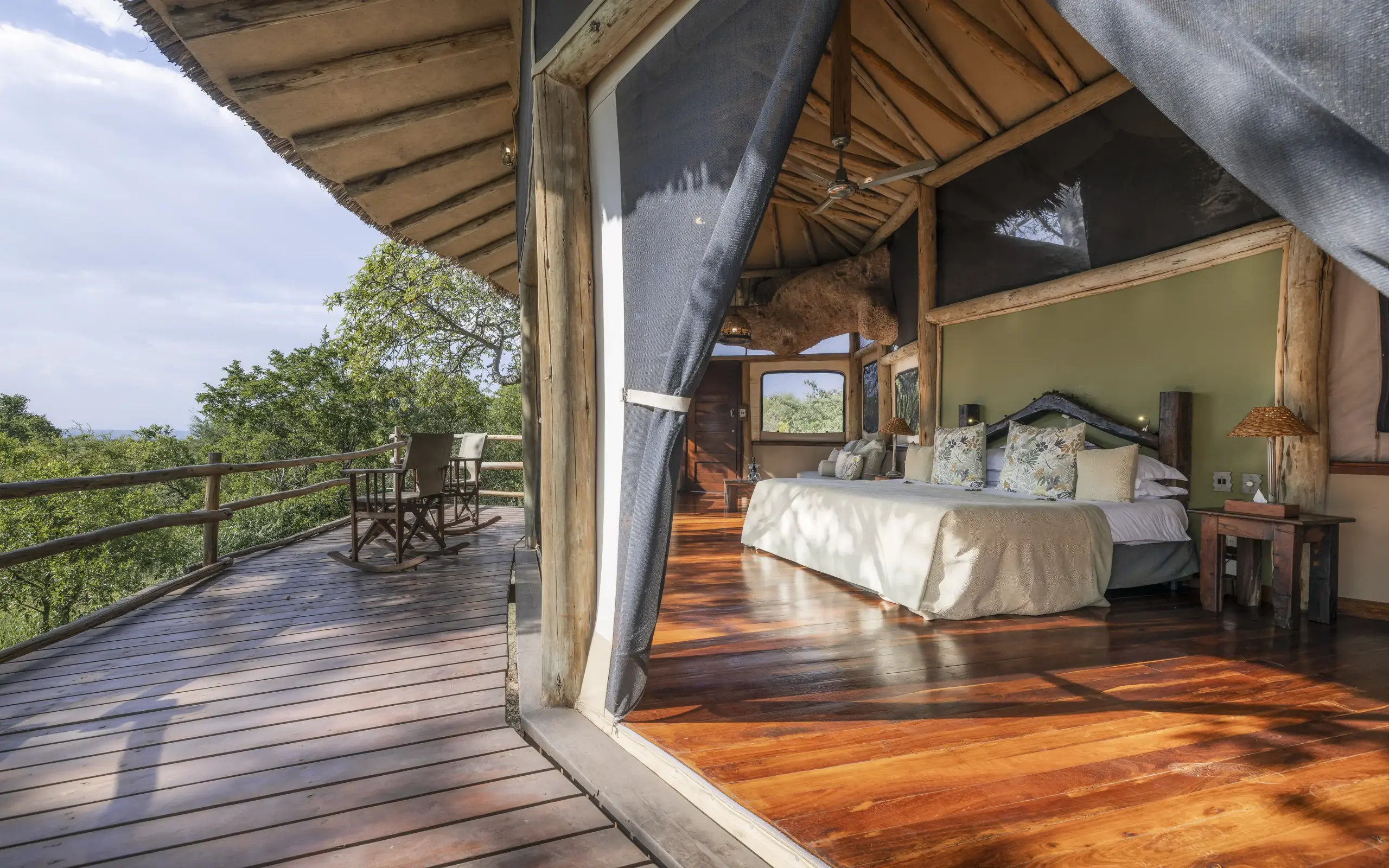 Luxury safari tent bedroom with open deck overlooking woodland landscape, Tarangire Treetops, Tarangire National Park, Tanzania