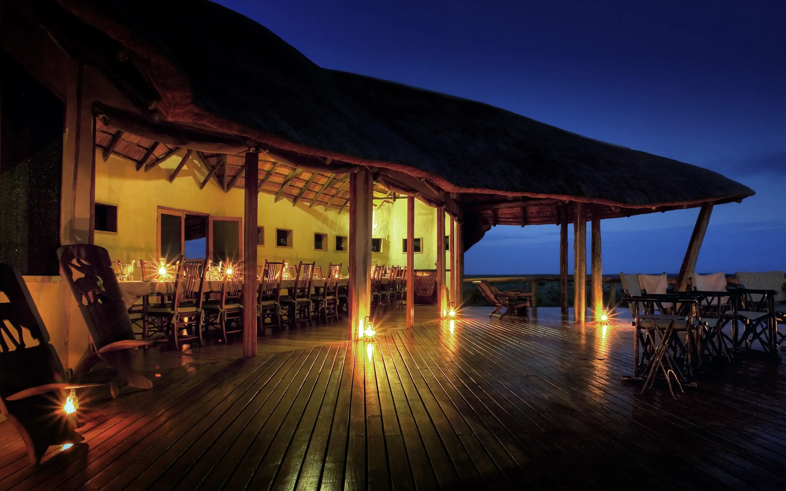 Illuminated wooden deck overlooking savanna at twilight, Tau Pan Camp, Central Kalahari, Botswana