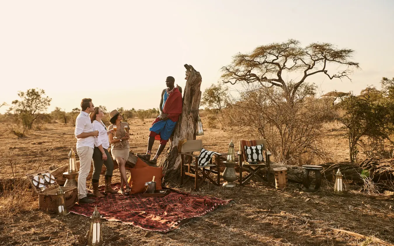 Guests gathered at outdoor safari camp under acacia tree, Tawi Lodge, Amboseli and Chyulu Hills, Kenya