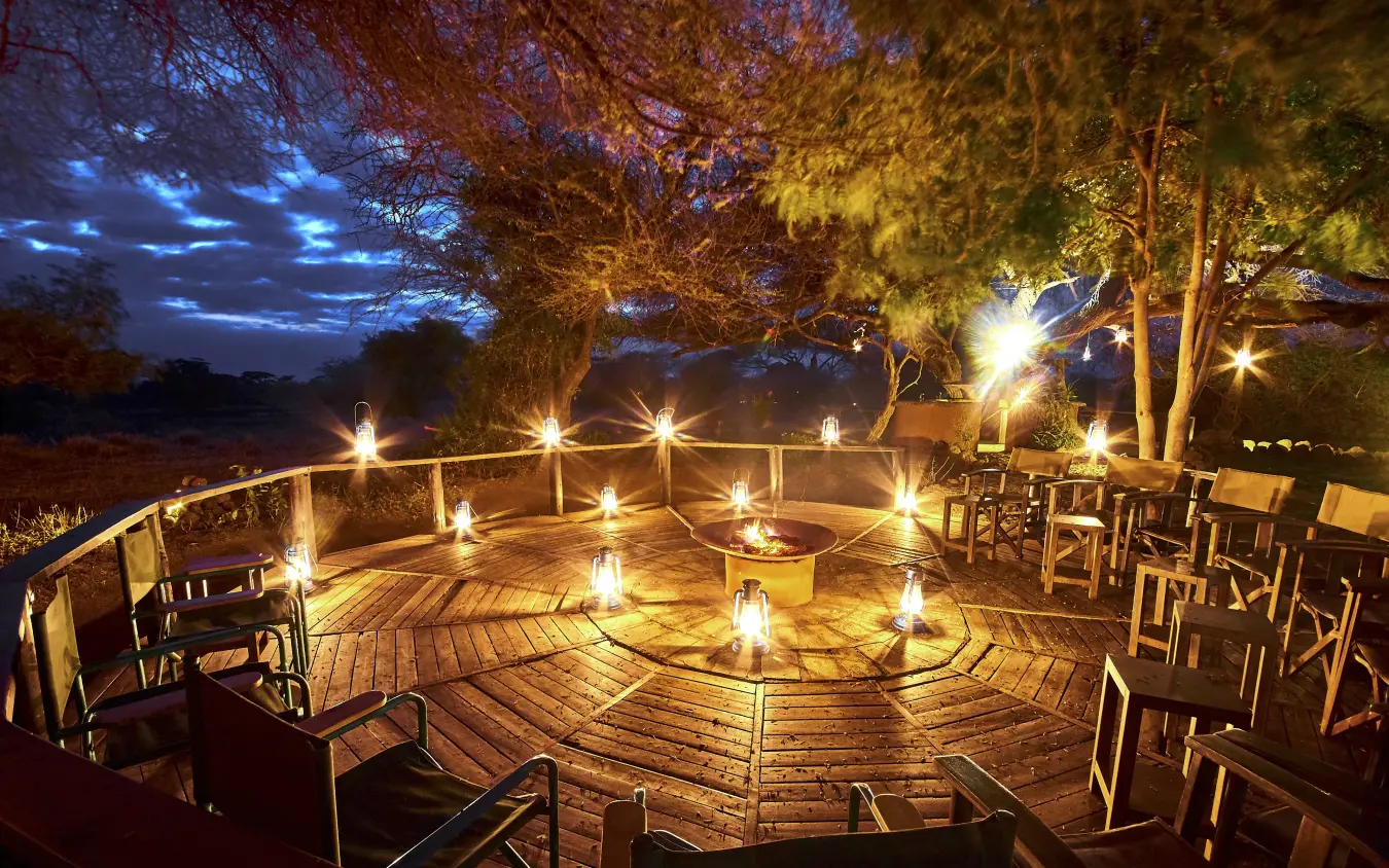 Wooden deck with lanterns and seating at dusk, Tawi Lodge, Amboseli and Chyulu Hills, Kenya