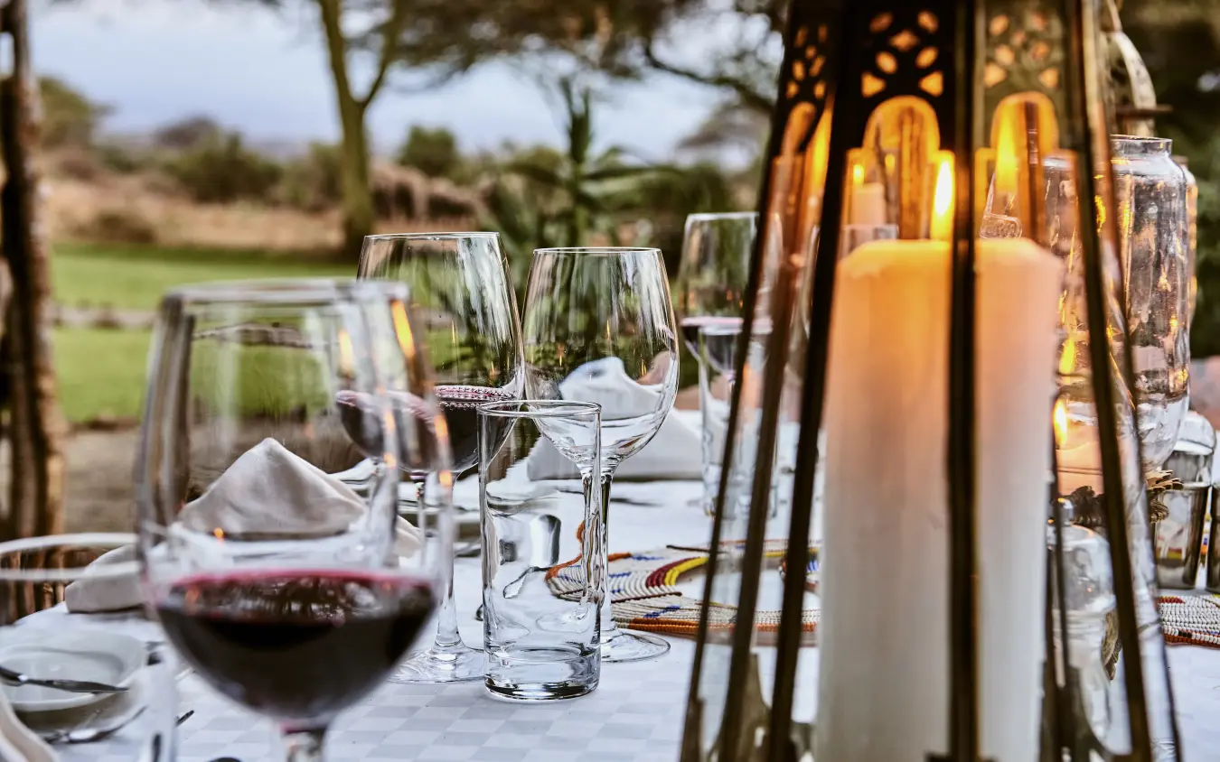 Outdoor dining table set with wine and glassware overlooking savanna, Tawi Lodge, Amboseli and Chyulu Hills, Kenya
